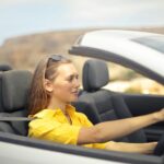 A young woman enjoys driving a convertible on a sunny day in Malta.